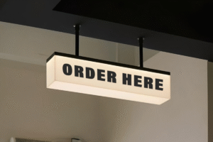 Pemasangan neon box acrylic menyala terang di depan ruko daerah Bekasi pada malam hari.