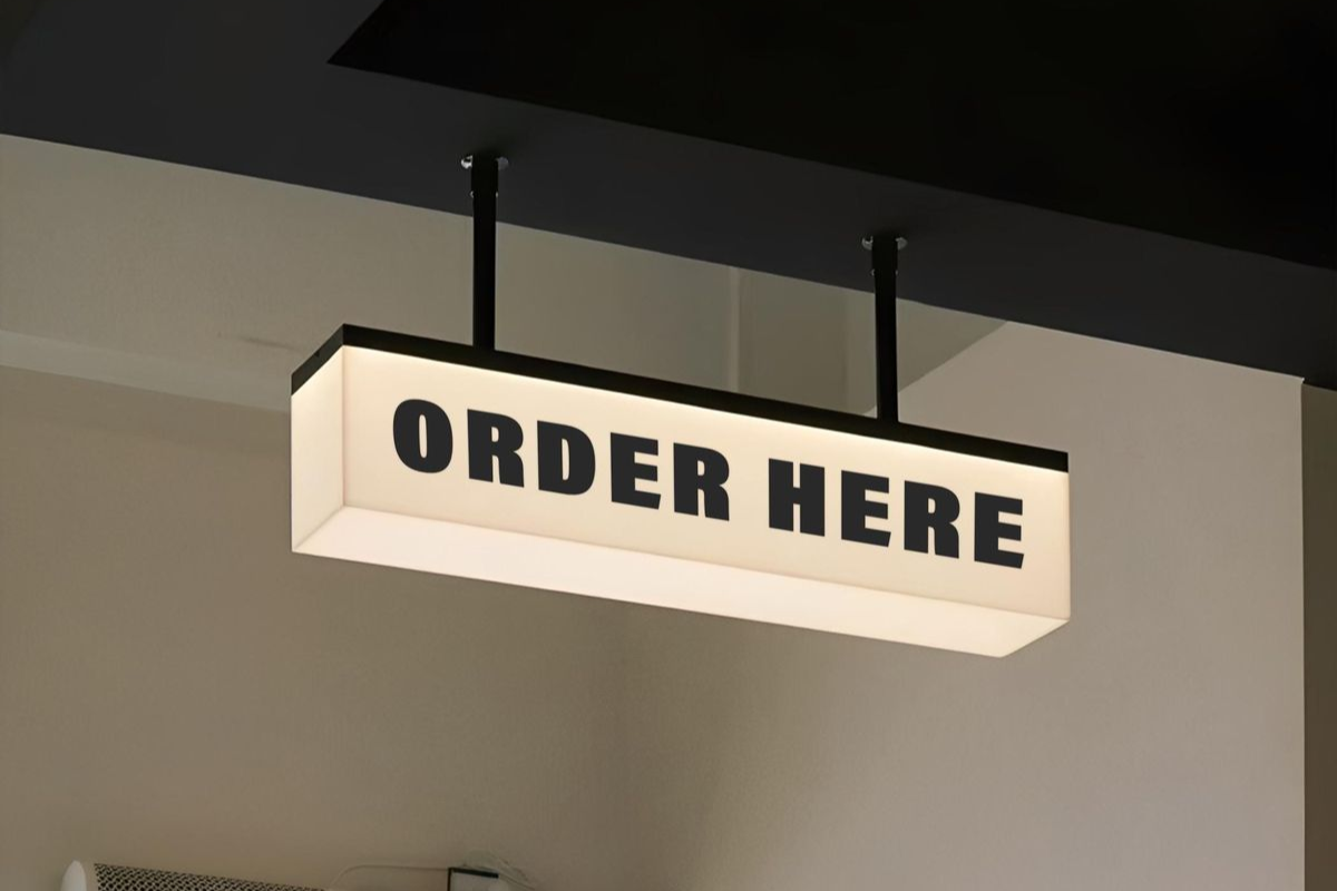 Pemasangan neon box acrylic menyala terang di depan ruko daerah Bekasi pada malam hari.